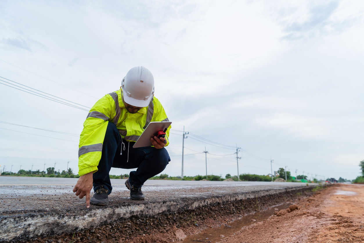 Monitoring pavement conditions - A male engineer checking the condition of pavement construction.