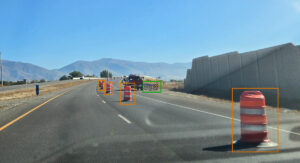 Dash camera image of a United States highway showing detections of work zone barrels and guardrail using Blyncsy's AI models.