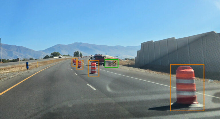 Dash camera image of a United States highway showing detections of work zone barrels and guardrail using Blyncsy's AI models.