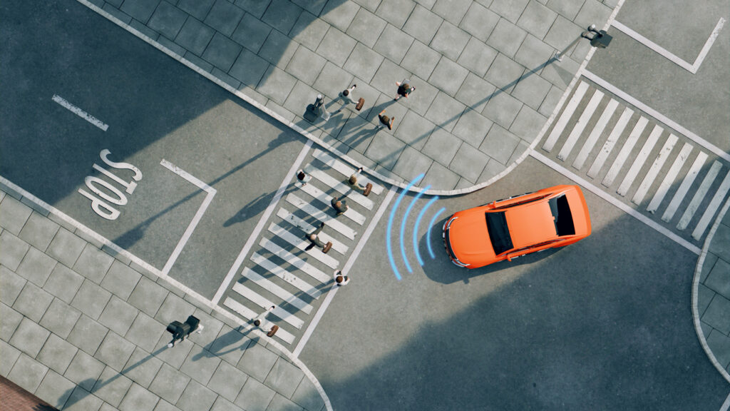 Aerial view of a bright orange car driving on a street.
