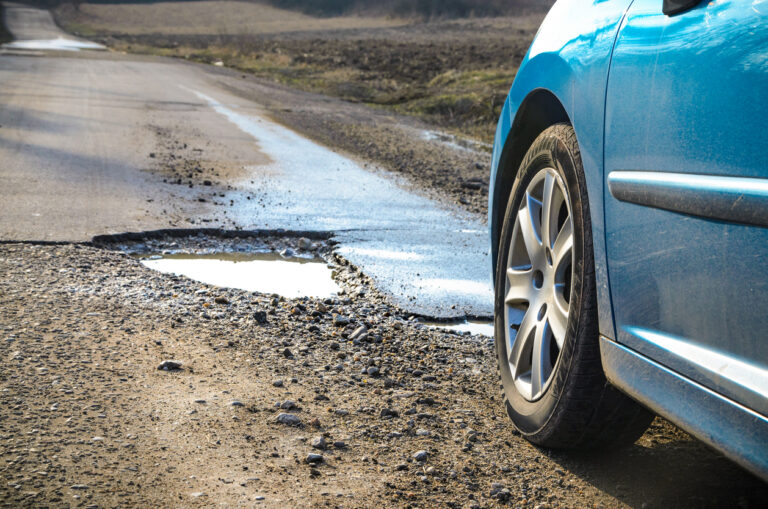Blue car and pothole on the road.
