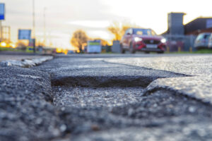 Potholes on the road with an approaching car.