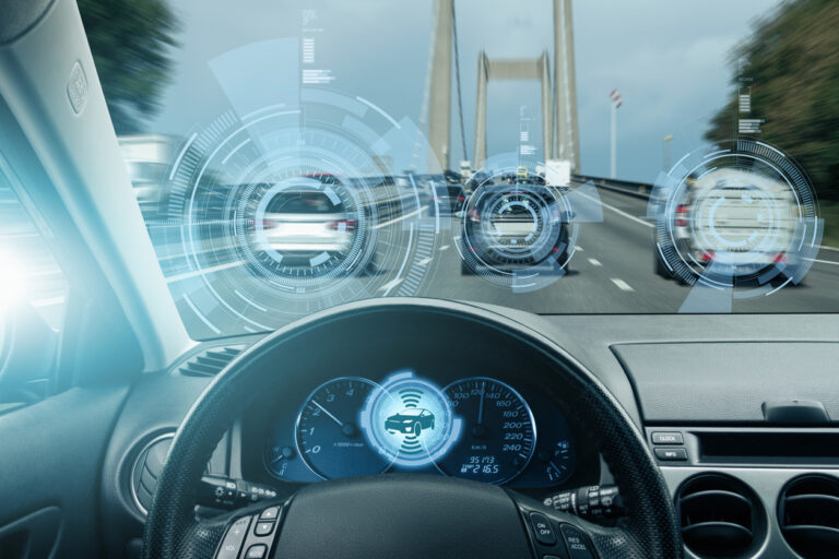 Cars on the road in front of a steering wheel.