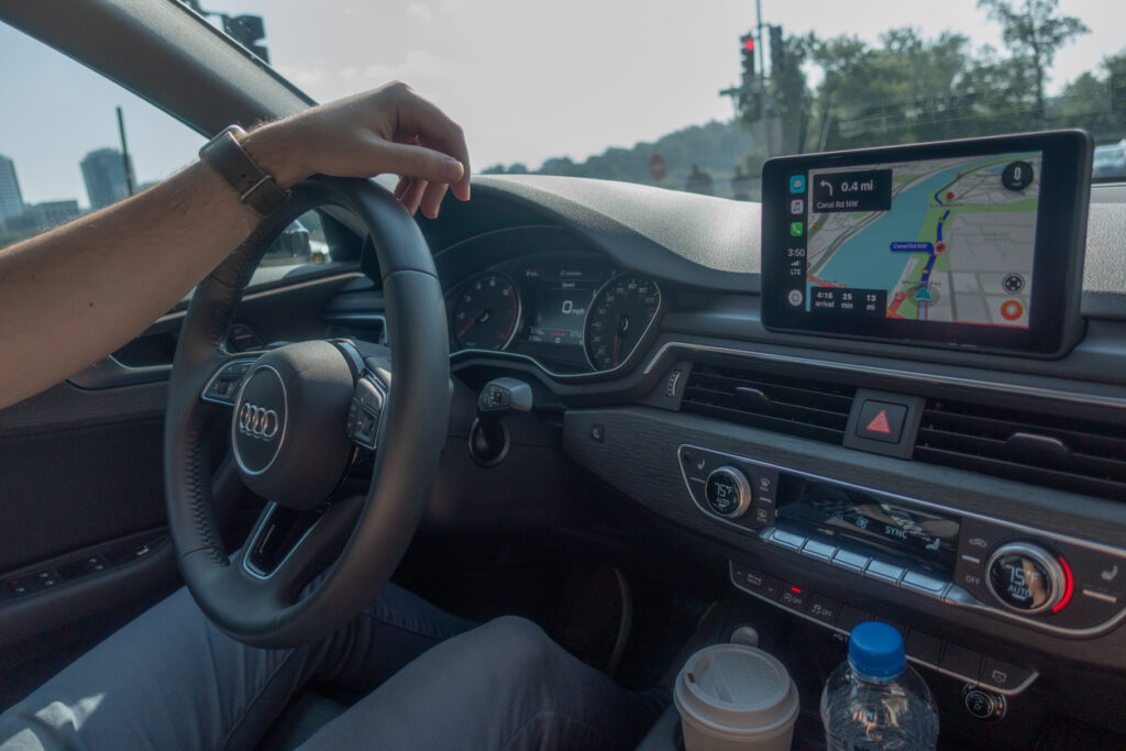Man driving while looking at a digital tablet with location map.