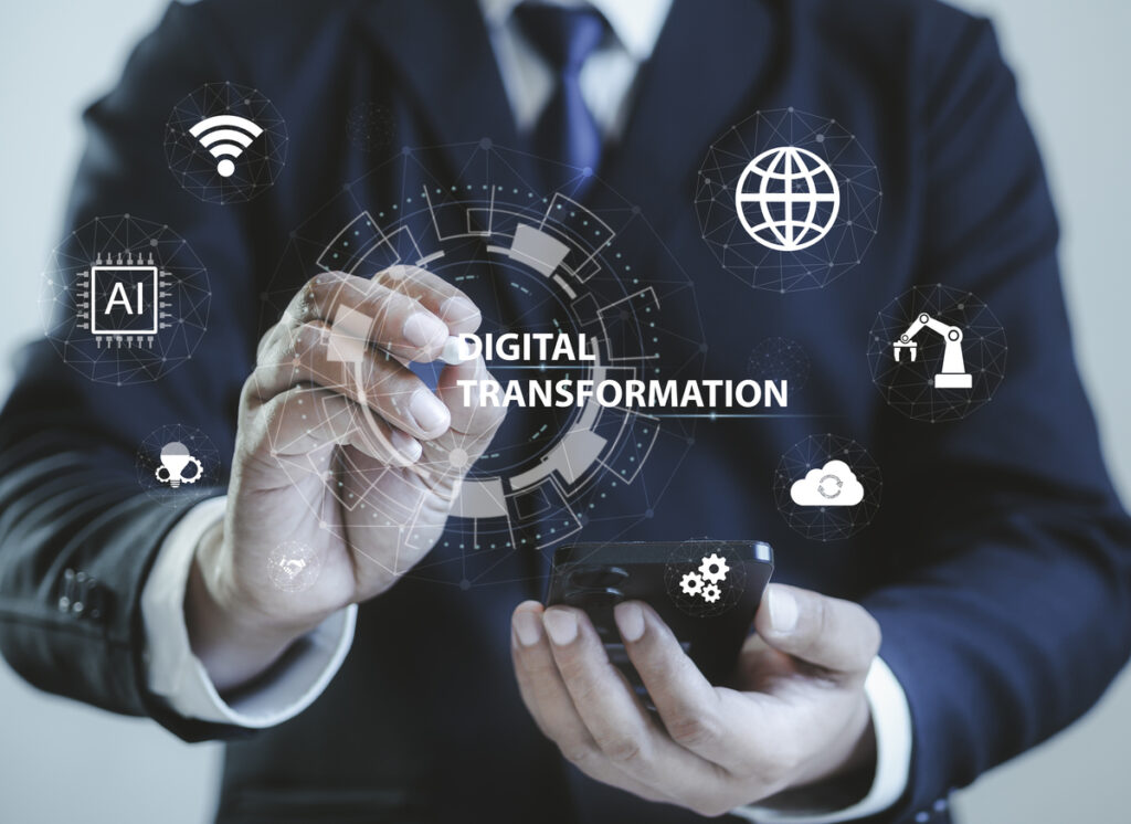 Businessman holding a smartphone while pointing to digital transportation icons on a virtual screen.