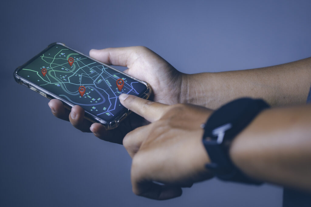 Man holding a smartphone while searching on a location map.