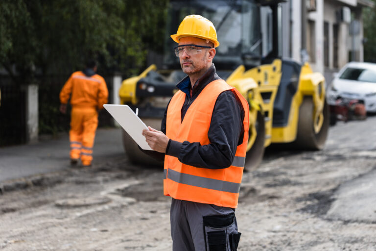 AI for Infrastructure Equity: Construction supervisor reviewing plans while overseeing roadwork in an urban area during the day