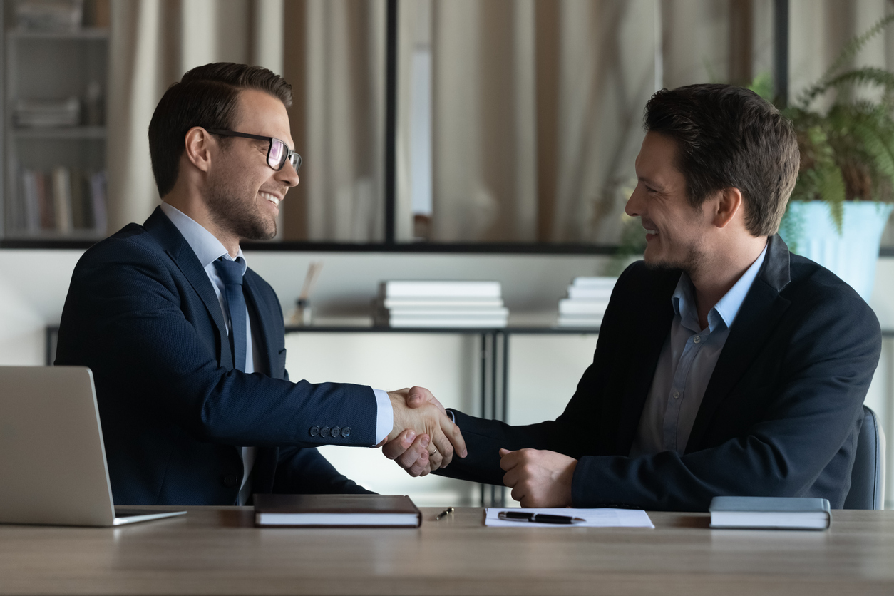 AI for Infrastructure Equity: Smiling businessmen give each other a handshake at an office.
