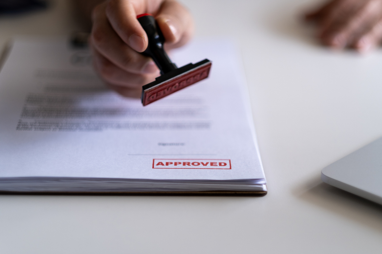 AI-powered imagery intelligence: Person stamping a stack of documents with a red “Approved” sign.