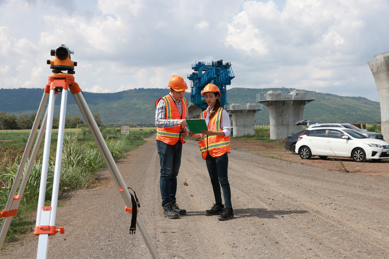 AI-powered imagery intelligence: Surveyors with survey equipment on a construction site doing manual inspection.