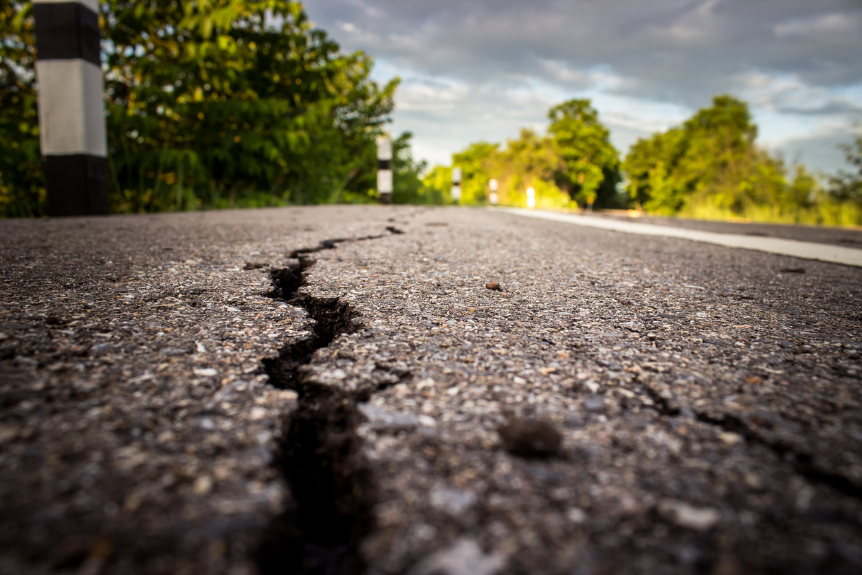 Pothole Lifecycle Management: Close-up view of a road showing early microcracks forming on the asphalt surface under sunlight.