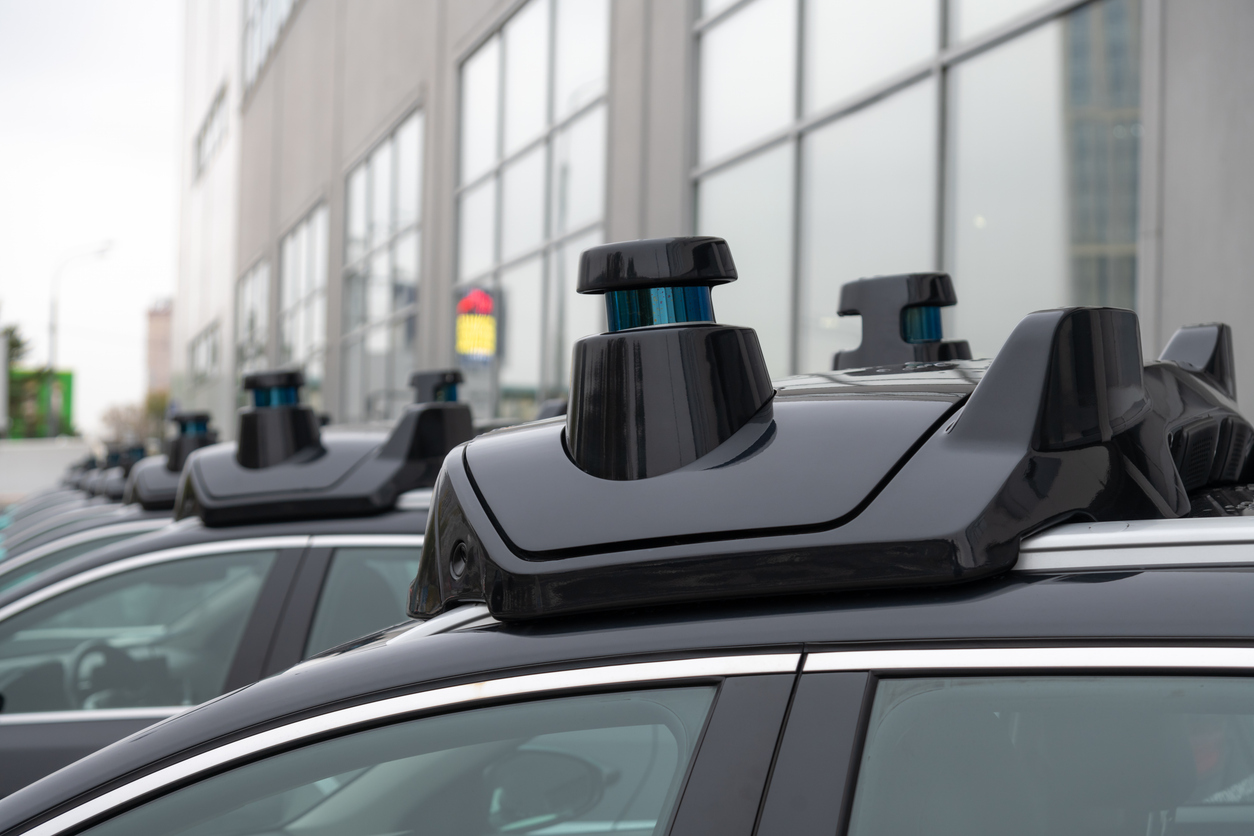 Connected and Autonomous Vehicle Infrastructure: A row of parked cars equipped with specialized rooftop sensors and technology for autonomous driving.
