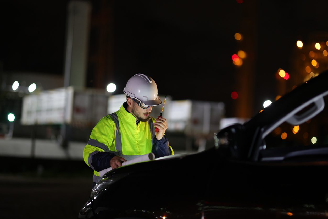 FHWA retroreflectivity compliance - an officer doing nighttime inspection while looking at a blueprint on top of his car’s dashboard.